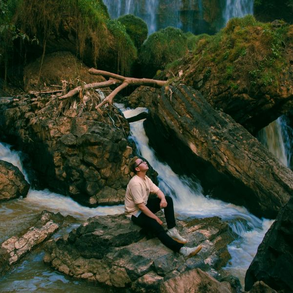 Person sitting calmly outdoors with a serene landscape background.