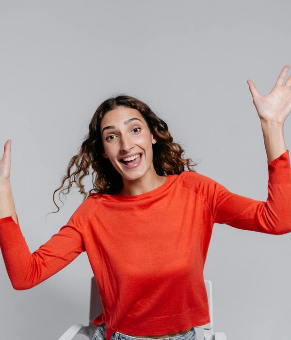 Woman with a positive expression mid-movement in a bright studio.